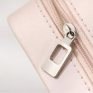 Détail de la fermeture éclair argentée sur boîte à bijoux nomade rose pâle en cuir lisse.