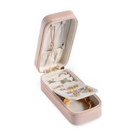 Boîte à bijoux nomade allongée rose avec compartiments et rangement pour bagues et colliers.