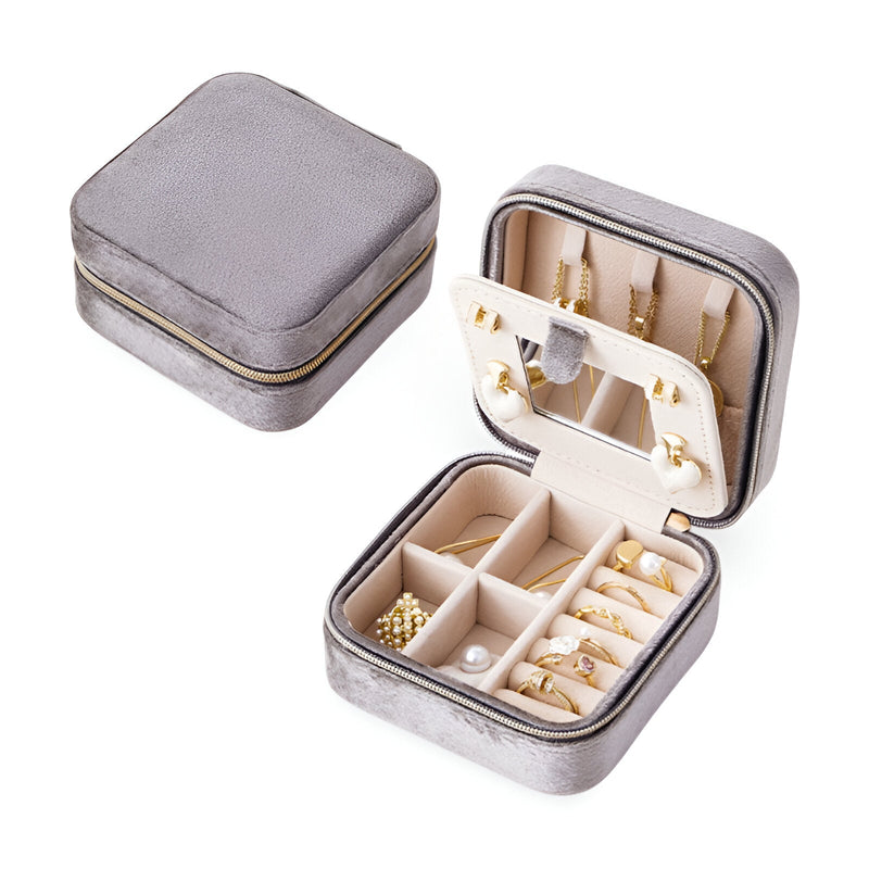 Boîte à bijoux nomade grise en velours avec compartiments et porte-bagues intégrés.