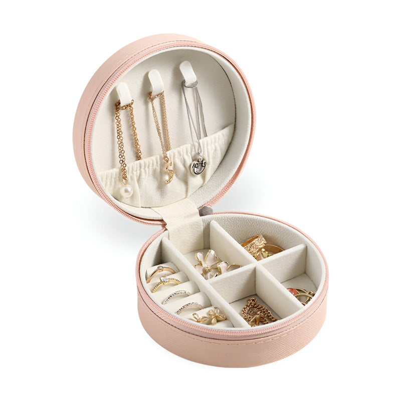 Boîte à bijoux nomade ronde rose avec compartiments et pochettes pour rangements variés.