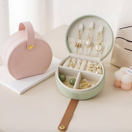 Boîte à bijoux nomade ronde vert menthe avec compartiments et rangements pour bagues et boucles d'oreilles.