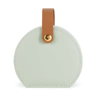 Boîte à bijoux nomade ronde en cuir vert pâle avec anse marron en cuir et bouton doré.