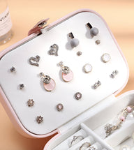 Boîte à bijoux nomade rose clair format moyen avec support blanc pour boucles d’oreilles et compartiments organisateurs.