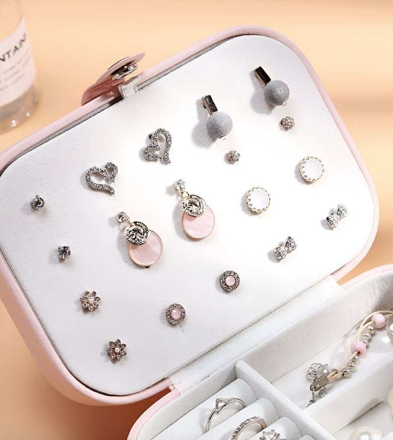 Boîte à bijoux nomade rose clair format moyen avec support blanc pour boucles d’oreilles et compartiments organisateurs.