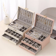 Deux grandes boîtes à bijoux nomades ouvertes, modèle Adriana, avec multiples tiroirs et compartiments, l’une rose blush,.