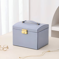 Boîte à bijoux nomade bleu clair, grande capacité, fermeture dorée, poignée supérieure élégante.