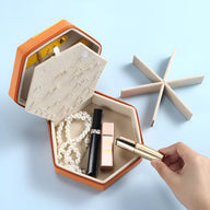 Boîte à bijoux hexagonale bicolore orange et jaune avec compartiments et bijoux à l'intérieur.