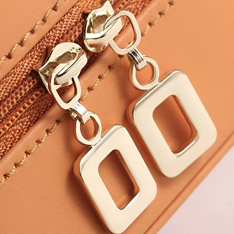 Fermeture éclair dorée sur boîte à bijoux hexagonale en cuir orange et jaune bi-colore.