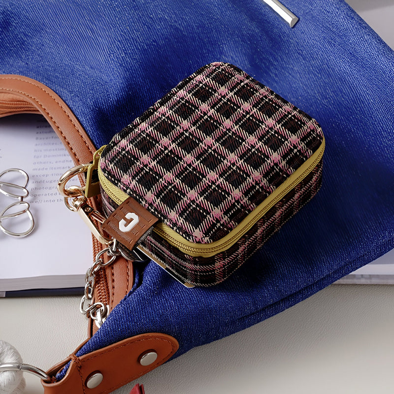 Boîte à bijoux nomade mini format à motif carreaux marron avec fermeture éclair dorée et détail cuir marron.