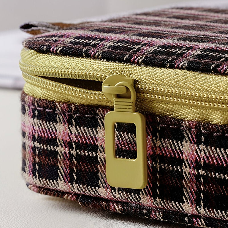 Boîte à bijoux marron à carreaux avec fermeture éclair dorée et tirette carrée.