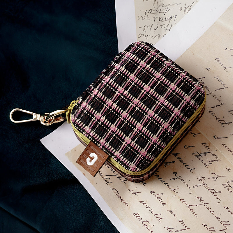 Boîte à bijoux nomade mini marron à carreaux roses avec fermeture éclair et crochet doré.