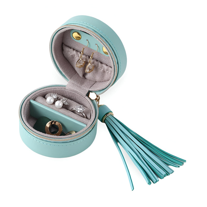 Boîte à bijoux ronde turquoise avec pompon assorti et intérieur organisé en tissu gris clair.
