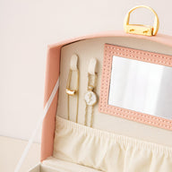 Boîte à bijoux rose avec miroir intégré, compartiment intérieur avec poche élastique et fermoir doré.