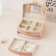 Boîte à bijoux rose avec miroir intégré, compartiments pour bijoux et tiroir supérieur ouvert, intérieur beige doux.