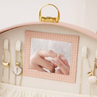 Boîte à bijoux rose avec miroir carré intégré et plusieurs compartiments pour chaînes et montres.
