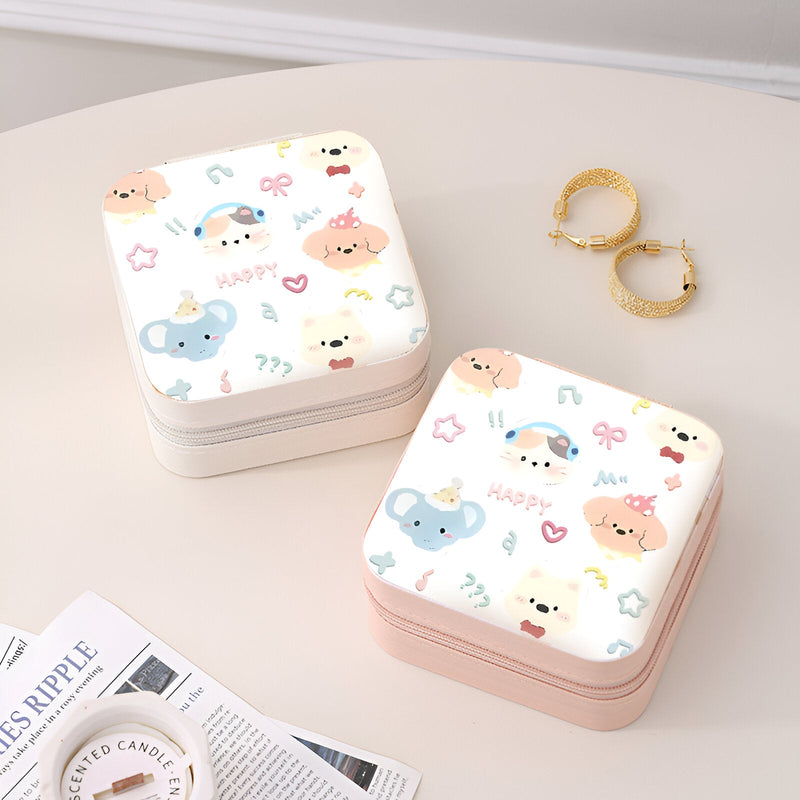 Deux boîtes à bijoux nomades carrées, motif animaux colorés, l’une blanche et l’autre rose pâle, posées sur une surface.