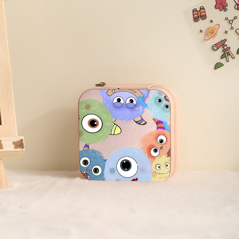 Boîte à bijoux rose avec motif monstres colorés aux grands yeux expressifs, format carré nomade.