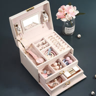 Boîte à bijoux nomade rose poudré avec multiples tiroirs, miroir intégré et rangement compartimenté.