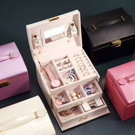 Boîte à bijoux rose poudré avec miroir, multiples tiroirs organisateurs et compartiments pour bijoux.