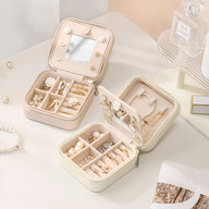 Boîte à bijoux nomade beige avec miroir intégré et compartiments pour assortiments variés.