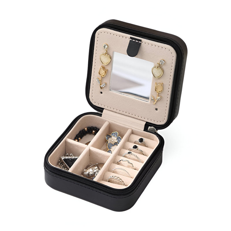 Boîte à bijoux nomade noire petite format avec miroir intégré et compartiments pour bagues et boucles d’oreilles.