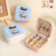 Petite boîte à bijoux rose avec compartiments séparés et crochets sur le couvercle, décor chiens colorés.