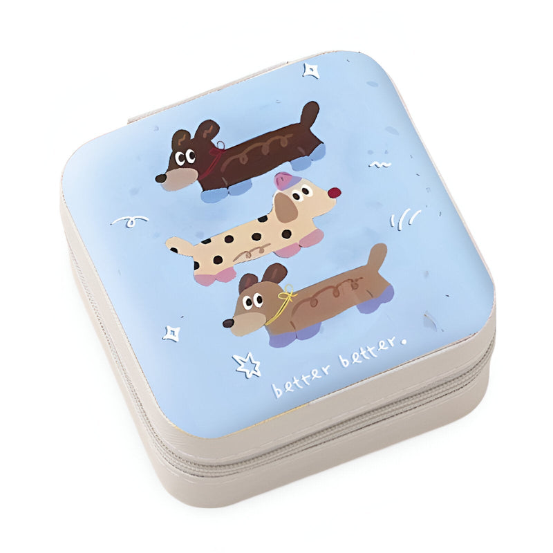 Boîte à bijoux nomade bleue avec illustration enfantine de trois chiens stylisés.