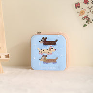 Boîte à bijoux nomade rose avec illustration enfantine de trois chiens joyeux.