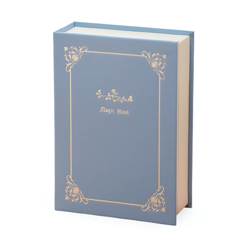 Boîte à bijoux nomade bleu style livre avec ornements dorés délicats et titre "Magic Book" sur la couverture.