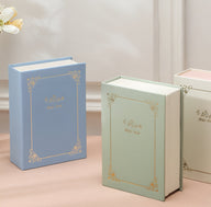 Boîte à bijoux nomade bleue aspect livre avec motifs dorés élégants.