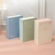 Trois boîtes à bijoux nomades style "Magic Book" en vert, bleu et rose pastel avec motifs dorés élégants.