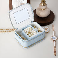 Boîte à bijoux nomade bleue en cuir avec miroir intégré et compartiments pour bagues et bijoux.