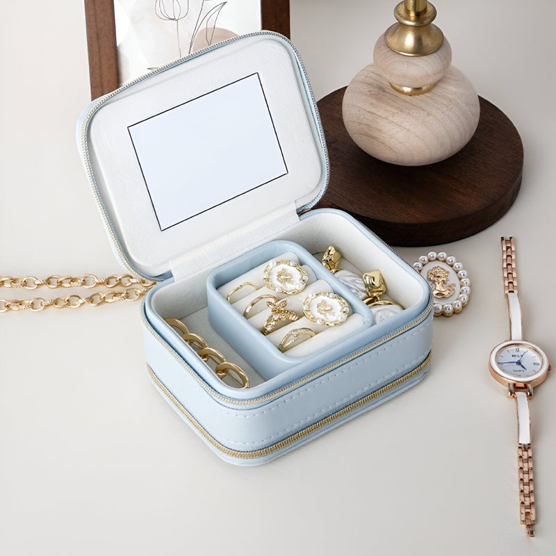 Boîte à bijoux nomade bleue en cuir avec miroir intégré et compartiments pour bagues et bijoux.