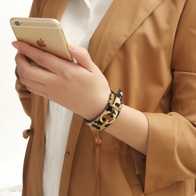 Bracelet à boucle en cuir au motif léopard beige et noir porté au poignet femme.