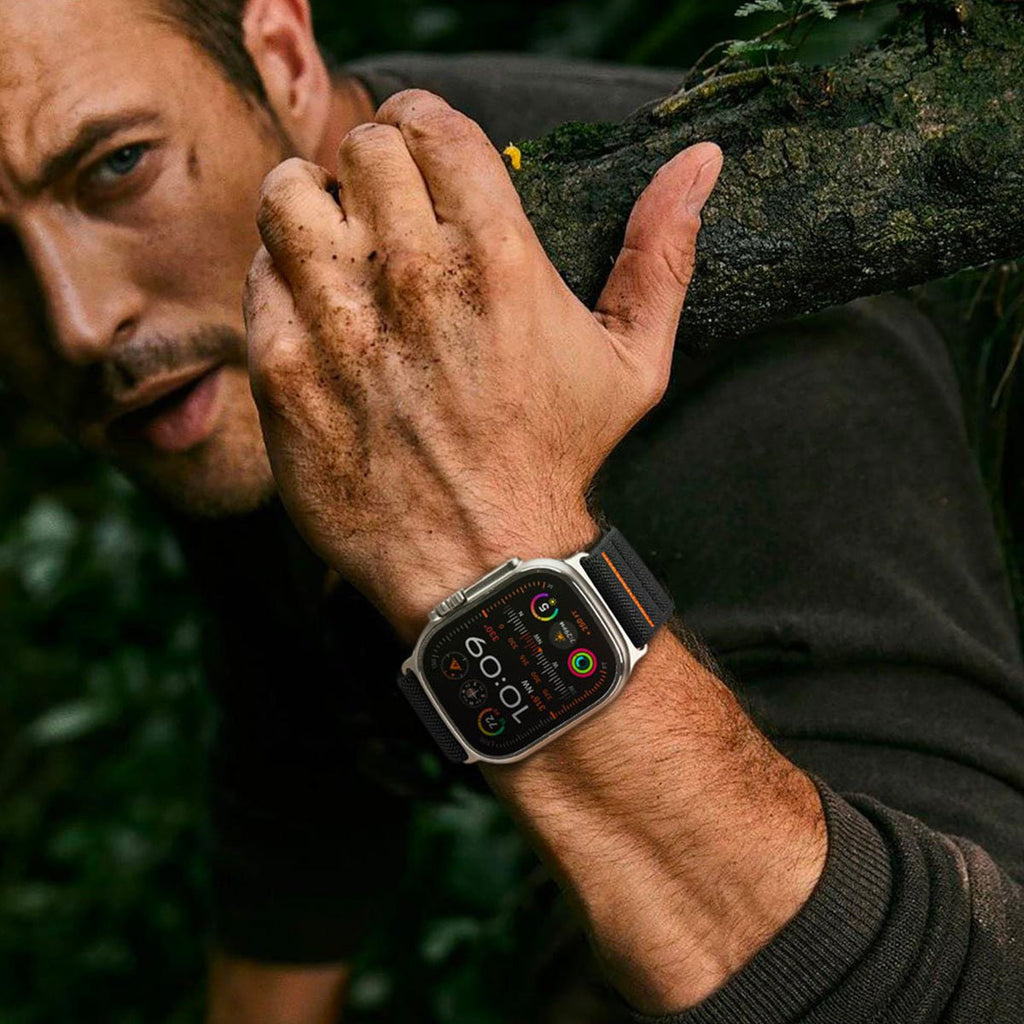 Bracelet tactique en nylon noir et orange pour Apple Watch avec boucle réglable, porté au poignet homme.