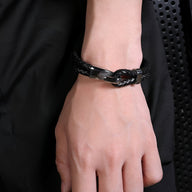 Bracelet noir en cuir tressé avec fermoir crochet en acier inoxydable sur poignet homme.