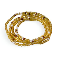 Bracelet en perles de résine élastique jaune doré avec accents blancs et marron, modèle enroulable Narwa.