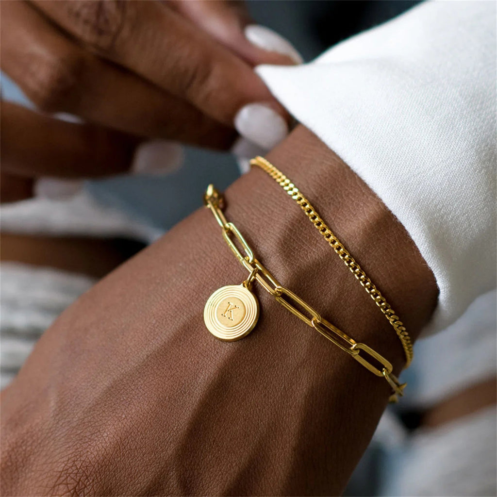 Armband mit rechteckigen Gliedern aus vergoldetem Edelstahl, personalisierbarer Anhänger in Medaillenform mit Buchstabe, elegante Kettenglieder im Büroklammer-Stil, Modell Calvina