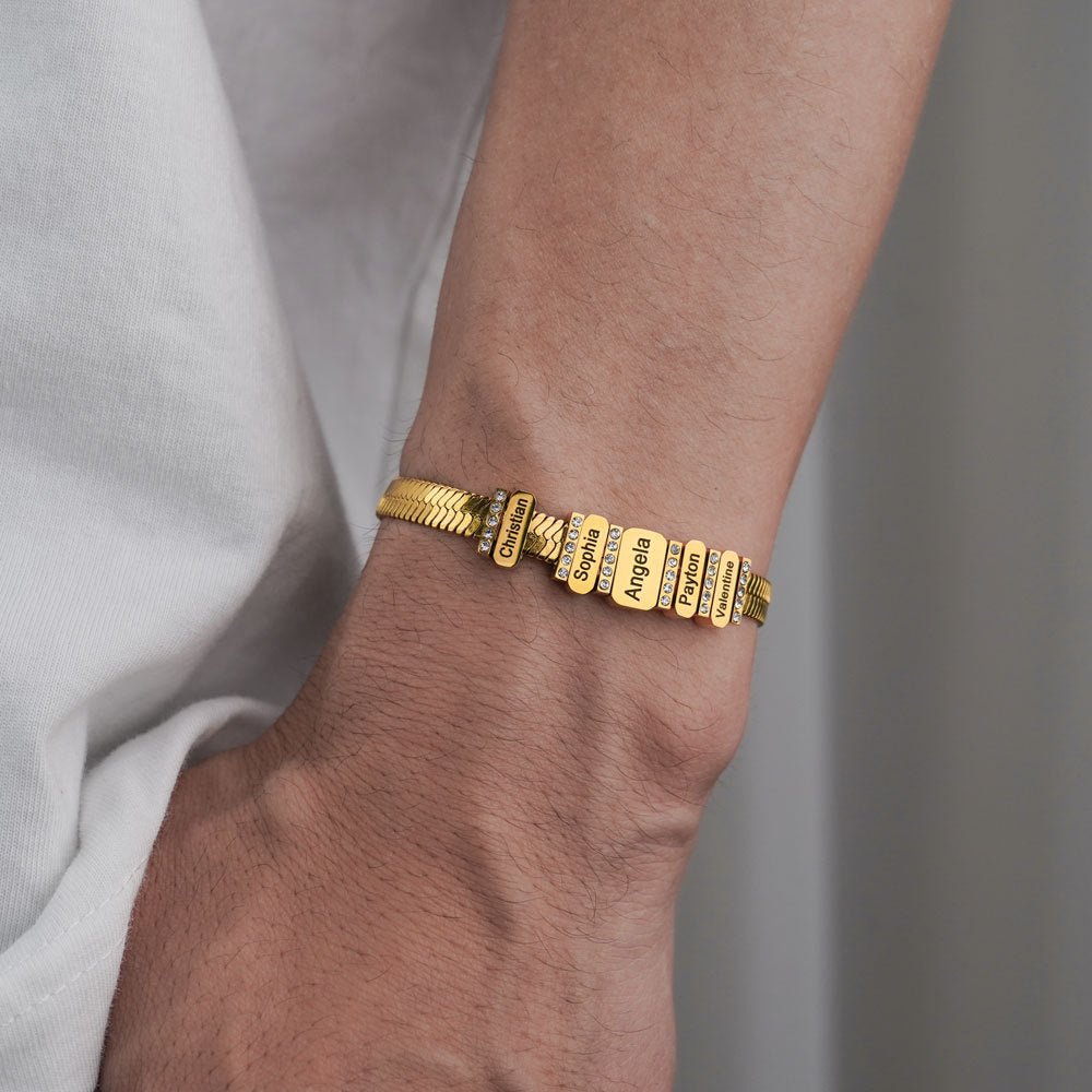 Bracelet à mailles serpent doré en acier inoxydable avec noms gravés et zircons brillants, ajusté au poignet.