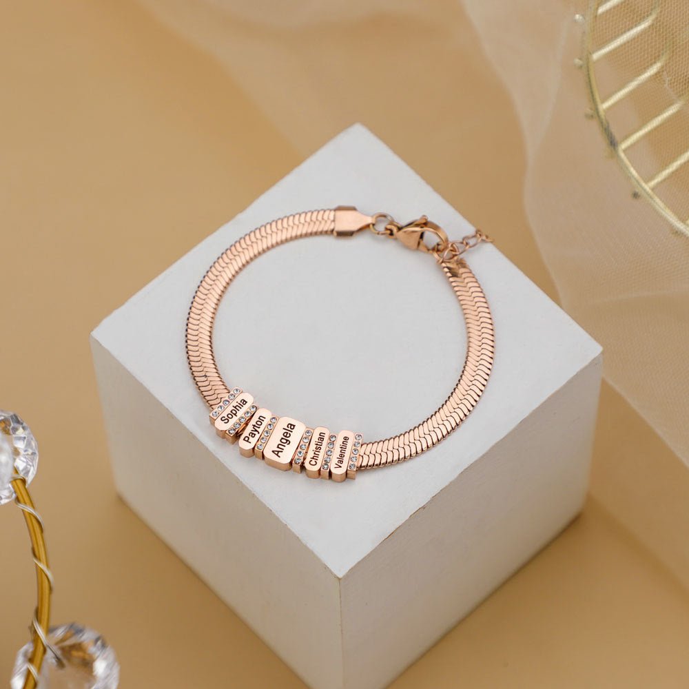 Bracelet serpent en acier inoxydable rose doré avec pendentifs lettres gravées et zircons brillants.