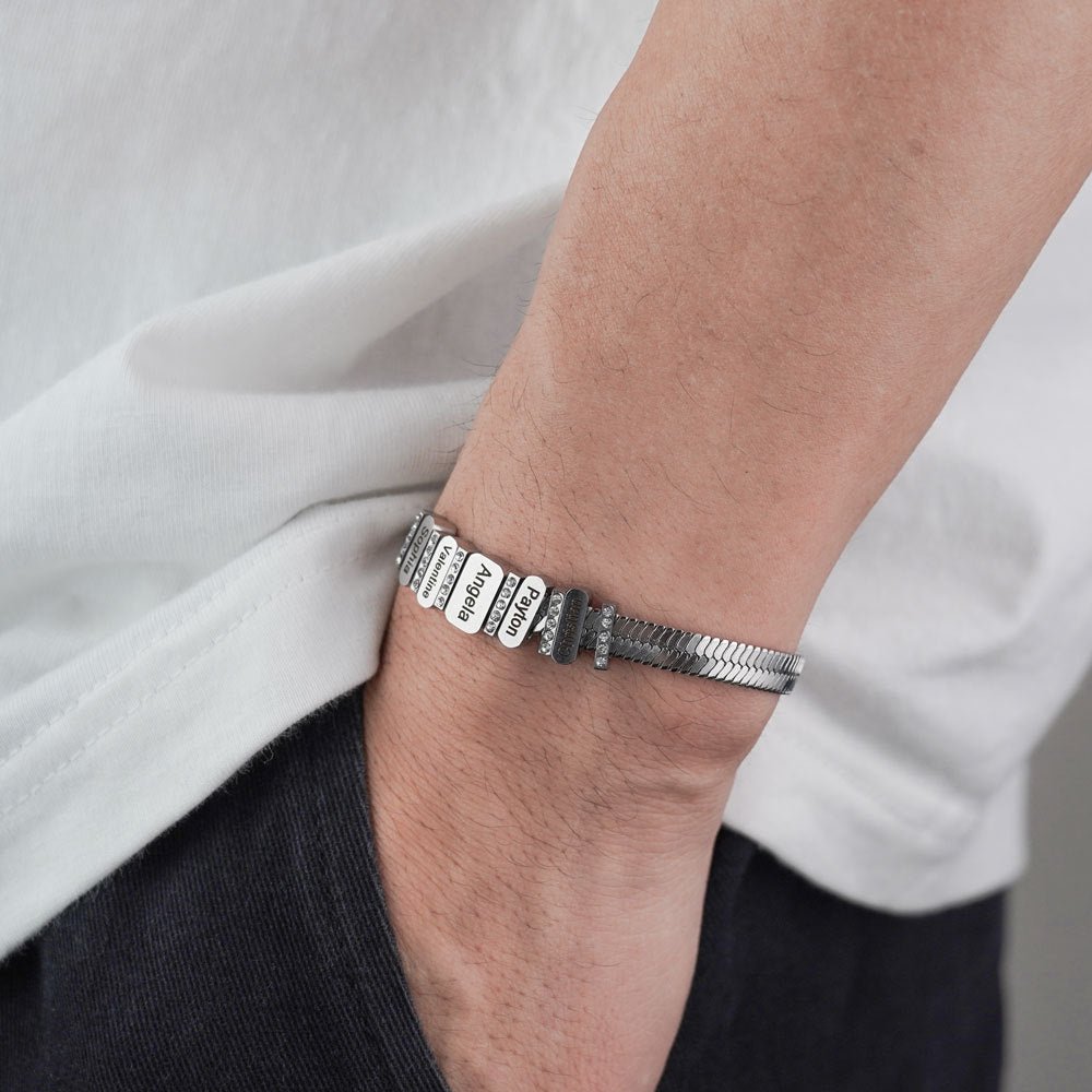 Bracelet serpent en acier inoxydable argenté avec plaque gravée et zircons brillants porté au poignet.