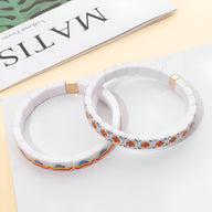 Bracelet en acrylique blanc avec motifs floraux colorés, finition carrée élégante.