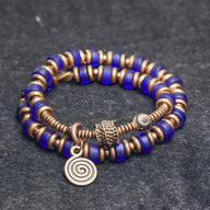 Bracelet à perles bleu en verre et anneaux en cuivre avec pendentif spirale pour femme.