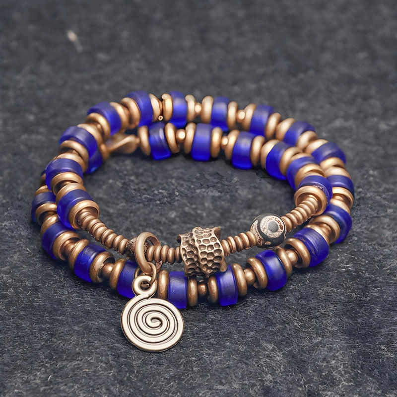 Bracelet à perles bleu en verre et anneaux en cuivre avec pendentif spirale pour femme.