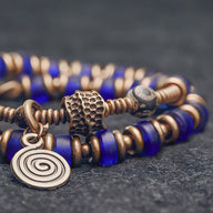 Bracelet femme à perles en verre bleu profond et éléments en cuivre avec breloque spirale design.