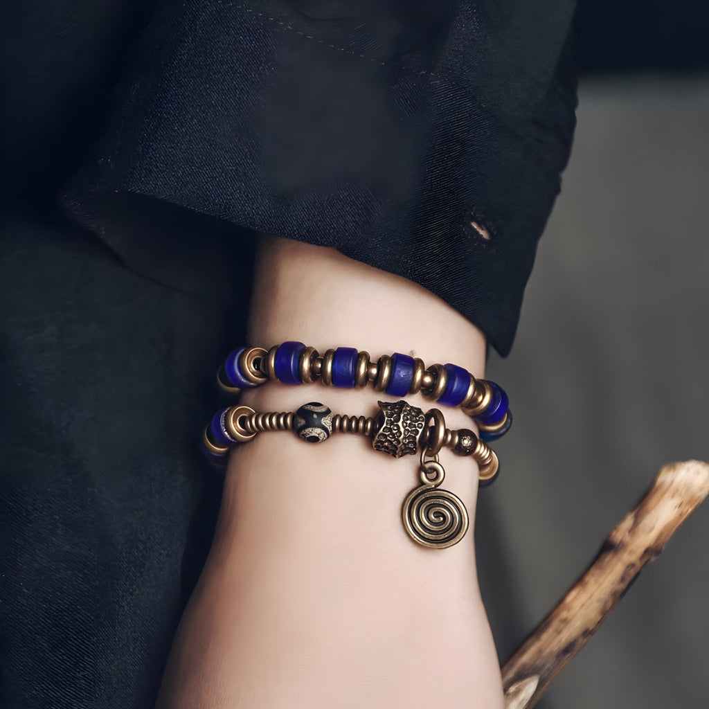 Bracelet femme en perles bleues avec détails en cuivre et pendentif spiralé antique.