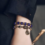Bracelet femme en perles bleues avec détails en cuivre et pendentif spiralé antique.