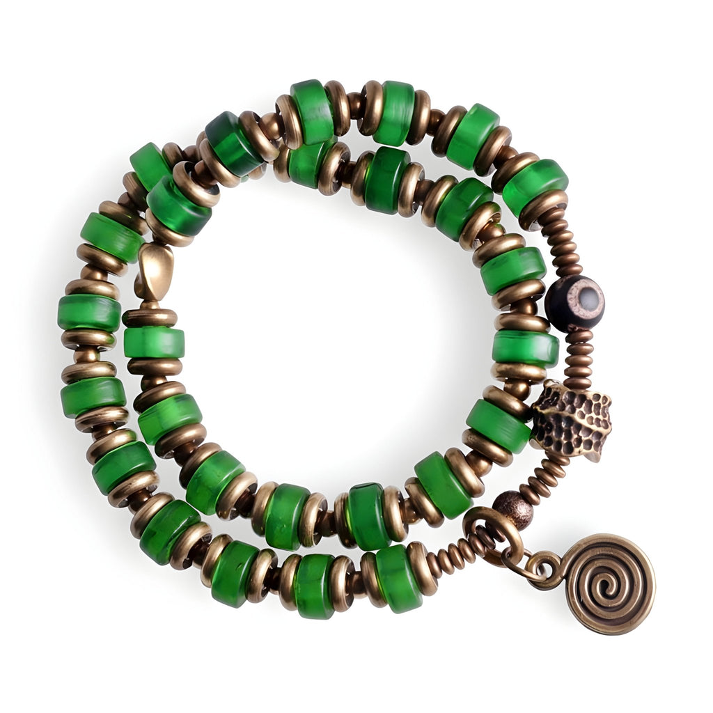 Bracelet à perles vertes en verre et cuivre avec breloque spirale, style bohème chic.