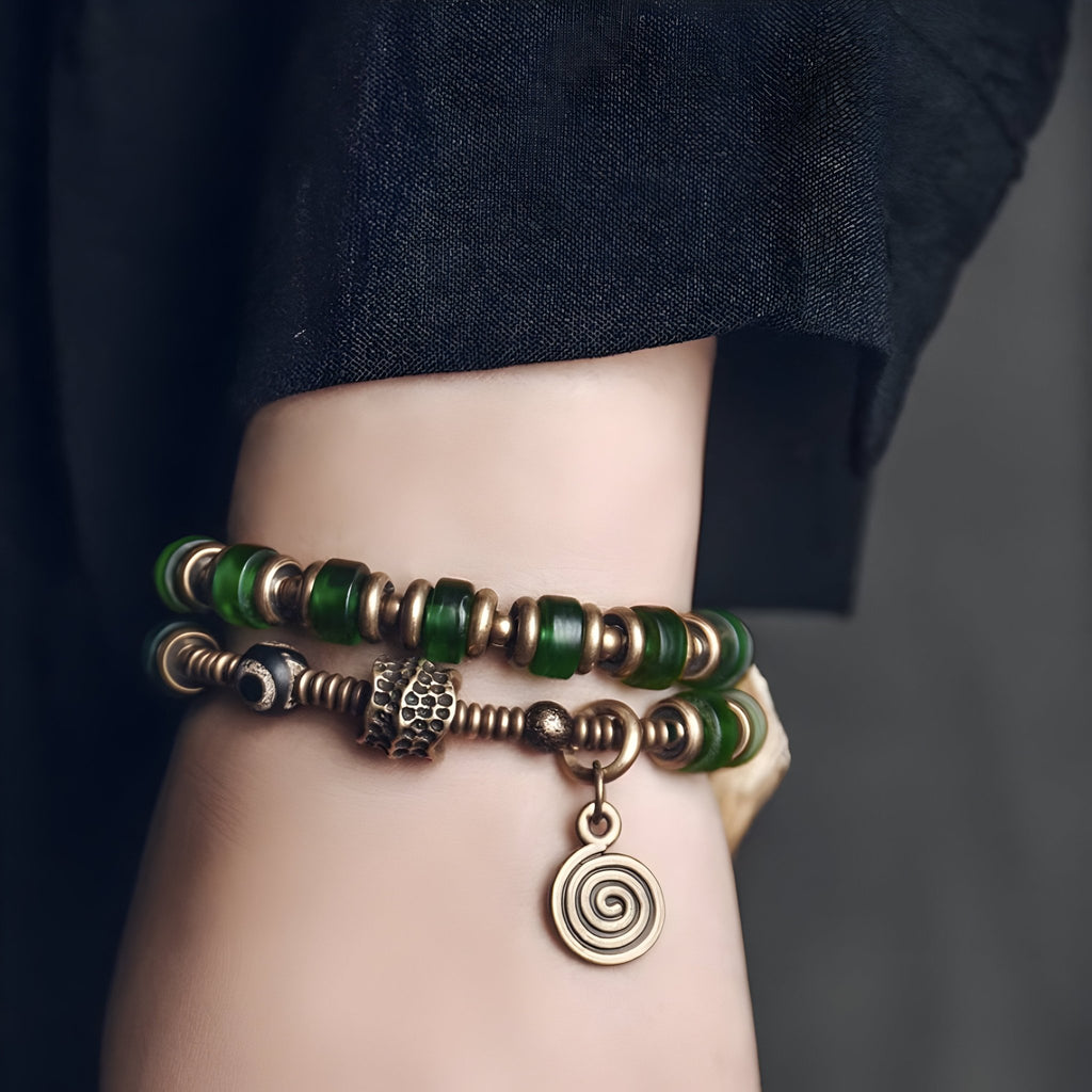 Bracelet femme en cuivre avec perles vertes en verre et pendentif rond spiralé.