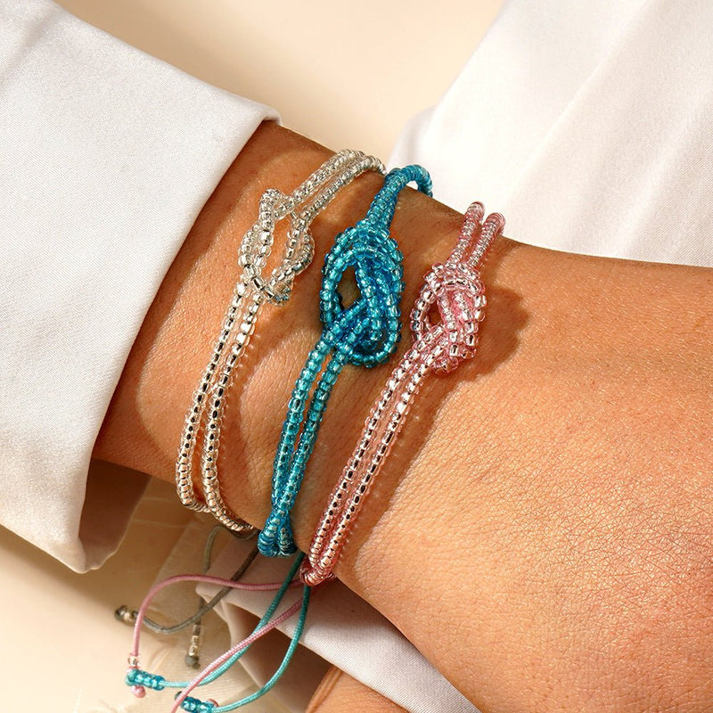 Bracelets ajustables à perles miyuki colorées avec nœuds centraux symboliques en bleu, rose et blanc nacré, cordons.